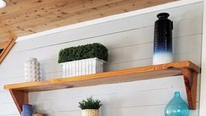 A wall with multiple wooden shelves holding various decorative items. - 3 BR/3 BA Village Walk House, Close to the Beach, Community Pool! (Port Aransas)