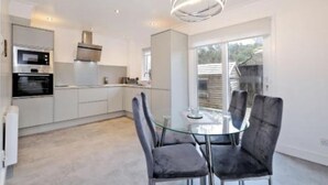 A modern kitchen with built-in appliances and a dining area with a glass table and chairs. - Contemporary HIGHLAND HOUSE close to town and Ben Nevis (Fort William)
