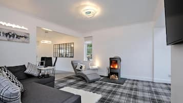 A modern living room with a fireplace, grey sofas, a plaid rug, and a minimalist design.