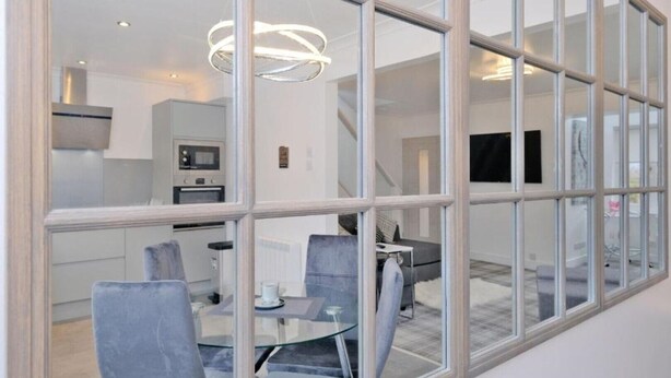 A modern interior with a dining area, kitchen, and living space visible through a large glass partition. - Contemporary HIGHLAND HOUSE close to town and Ben Nevis (Fort William)