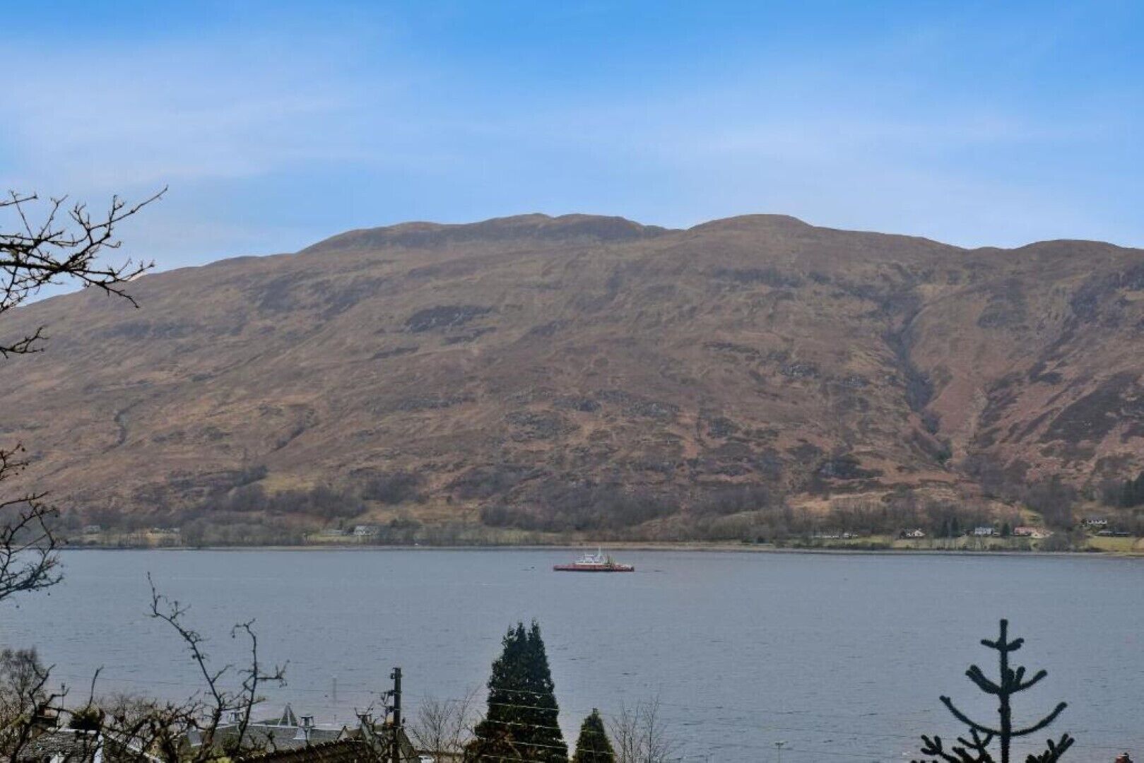 A lake with a boat, surrounded by mountains and sparse vegetation.