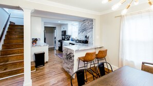 Una cocina moderna con una isla de mármol, suelo de madera y un comedor con mesa y sillas.