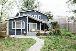 A two-story house with a covered porch and a small front yard.