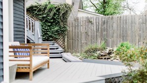 Una terraza de madera con un banco y escalones que llevan a una casa.