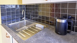 A kitchen with a stainless steel sink, a coffee maker, and a tiled backsplash. - The Yellow Nest, Studio at Victoire Square (Burdeos)