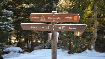 A wooden directional signpost in a snowy forest.