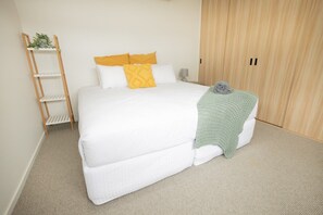 A bedroom with a bed, a wooden ladder, a wardrobe, and a small plant on the wall. - Seven Islands (Airlie Beach)