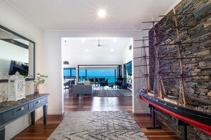 A spacious living area with a large window, a model ship, and a stone wall. - Seven Islands (Airlie Beach)