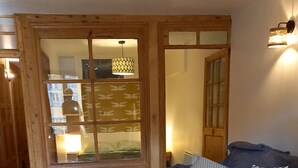 Une pièce chaleureuse avec un plancher en bois, un canapé agrémenté de coussins à motifs, un petit tabouret et une table sur laquelle est posée une plante.