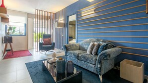 Una sala moderna con un sofá azul, un sillón rojo y una mesa de centro con objetos decorativos.