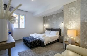 A bedroom with a bed, bedside table, lamp, and a decorative plant. - Beach front apartment in Marina di Ragusa (Marina di Ragusa)