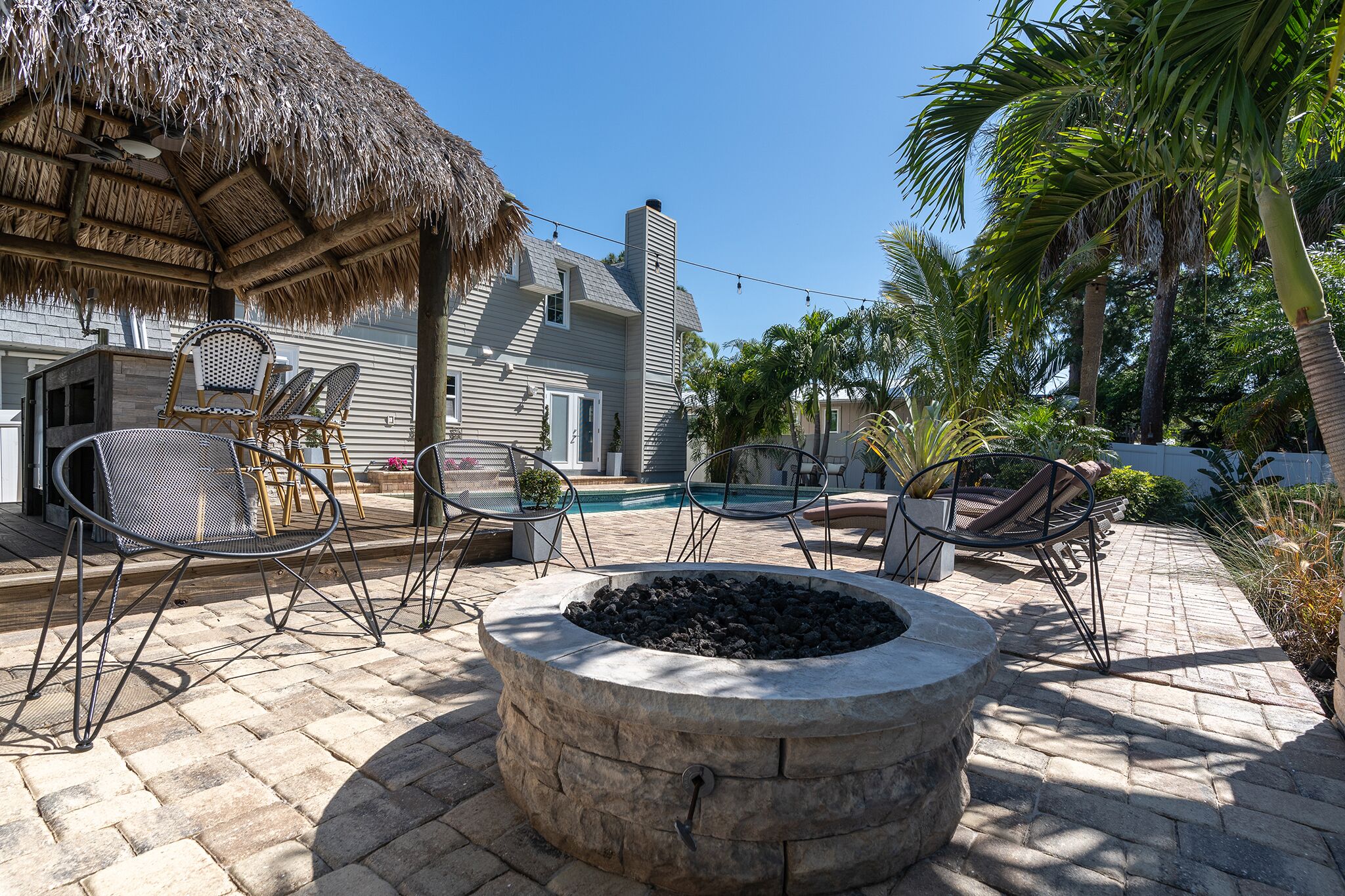 Un espace patio aménagé avec un foyer en pierre, du mobilier d’extérieur et une piscine.