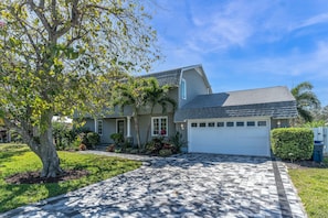 A single-story house with a garage, a paved driveway, and a well-maintained lawn.