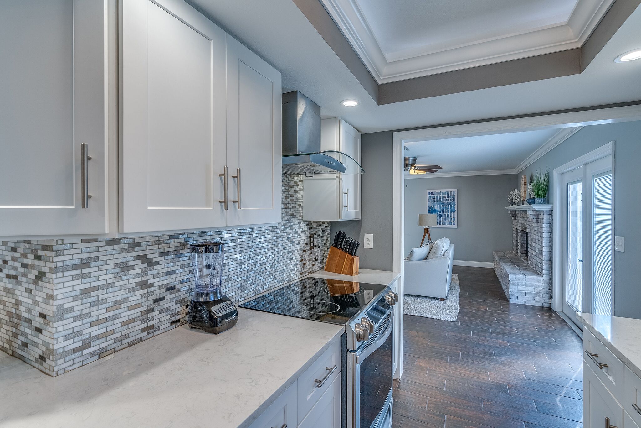 A modern kitchen with white cabinets, a black countertop, and a built-in stove.