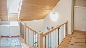 A wooden staircase with a railing, a white door, and a skylight in a room with wooden walls and a light-colored floor.