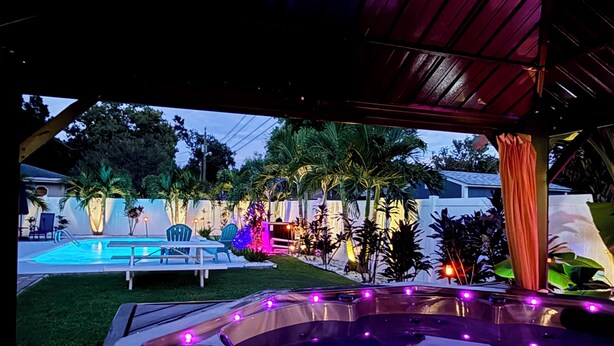 A hot tub with purple lighting, a pool, and outdoor seating. - Coastal Vibe • Private Heated Pool • Hot Tub • Near Beaches (Clearwater)
