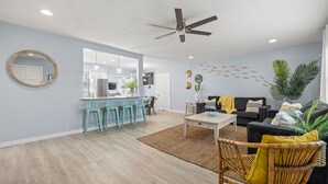A spacious living area with a dining area, a ceiling fan, and a kitchen in the background. - Coastal Vibe • Private Heated Pool • Hot Tub • Near Beaches (Clearwater)