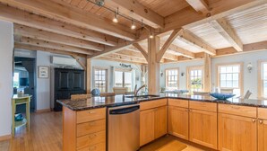 Une cuisine spacieuse dotée de meubles en bois, de plans de travail en granit et d’un grand îlot central.