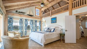 Une chambre à coucher avec un grand lit, une chaise, une armoire et une fenêtre avec des rideaux.
