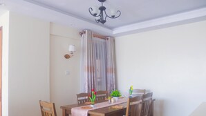 Un comedor con mesa de madera, sillas y una lámpara de araña.