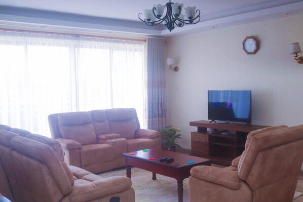 Ein Wohnzimmer mit zwei Sofas, einem Couchtisch, einem Fernseher und einer Chandelüster.
