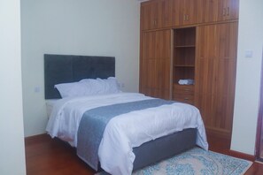 Ein Schlafzimmer mit Bett, Holzschrank und einem gemusterten Teppich.