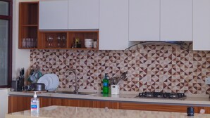 Una cocina con gabinetes blancos, un salpicadero estampado, un lavamanos y una estufa a gas.