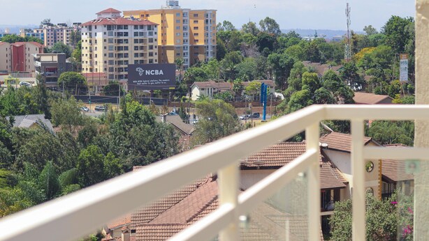 Vista de un área residencial con un cartel destacado de NCBA, rodeada de casas y vegetación.
