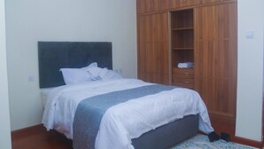 Un dormitorio con cama, armario de madera y mesita de noche.