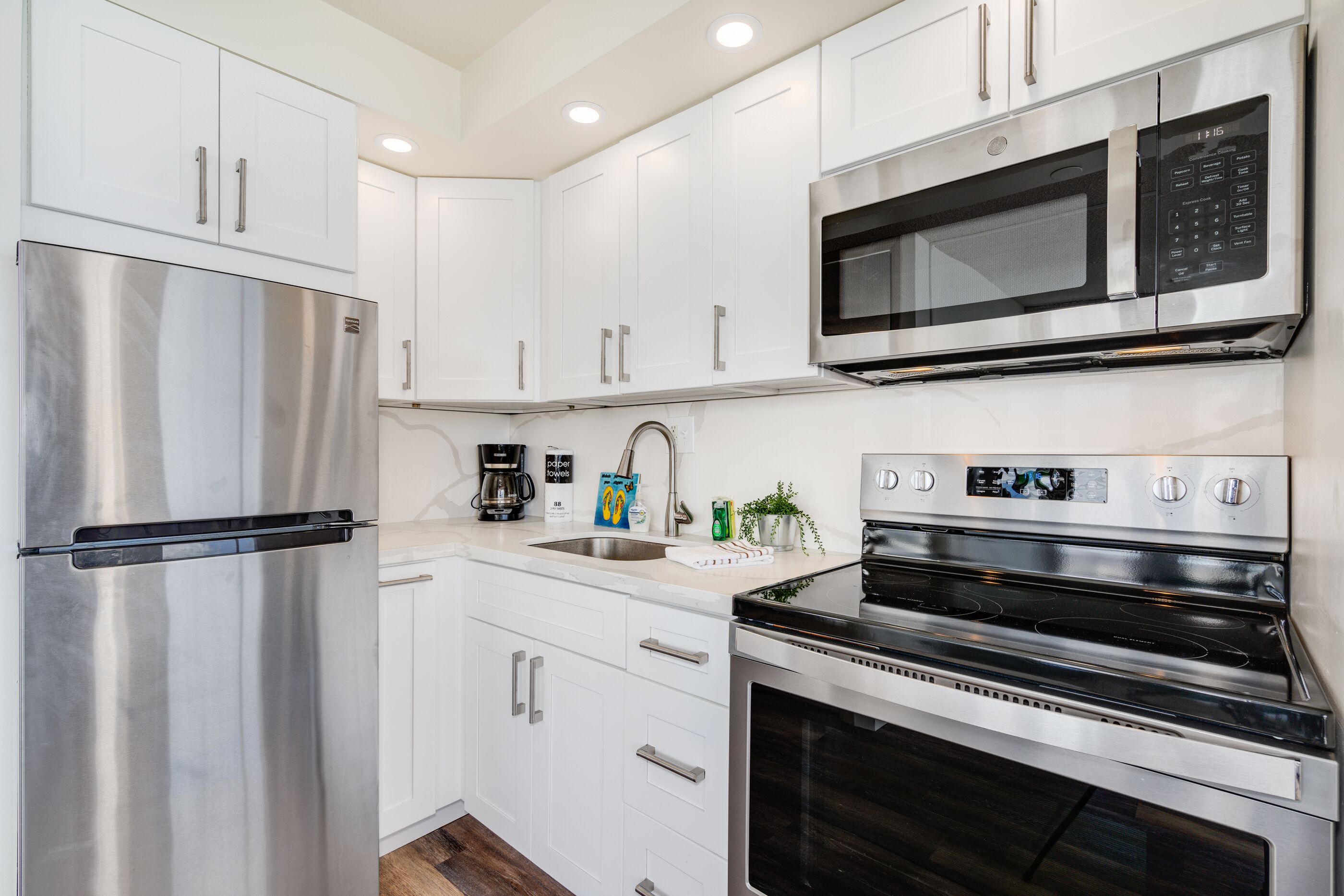 A modern kitchen with stainless steel appliances, white cabinetry, and a built-in oven.