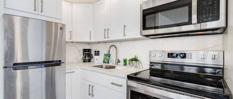 A modern kitchen with stainless steel appliances, white cabinetry, and a built-in oven.