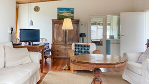 Una sala de estar con televisión, sofá, mesa de comedor y un mueble de madera.