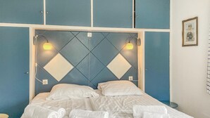 Habitación de hotel con cama, ropa de cama blanca y dos lámparas fijadas a la pared.