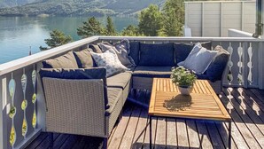 Una terraza con un sofá de mimbre, una mesa de centro de madera y una planta en maceta.