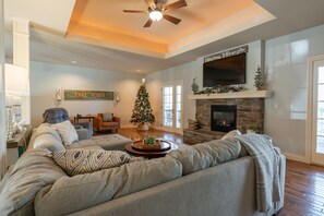 A spacious living room with a large gray sectional sofa, a fireplace, and a Christmas tree.