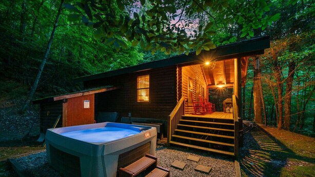 Eine Hütte mit Whirlpool, Holzterrasse und einer Treppe zu einer überdachten Veranda.