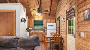 Ein Holzblockhaus-Innenraum mit Wohnzimmer, Essbereich und Küche.