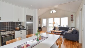 Eine moderne Küche mit weißen Schränken, einem Edelstahlkühlschrank und einem Essbereich mit einem weißen Tisch und Stühlen.