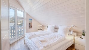 A bedroom with a large bed, a nightstand, a lamp, and a window with a view of a snowy landscape. - Awesome home in Krems II/Warderbrück with sauna (Krems II/Warderbrück)