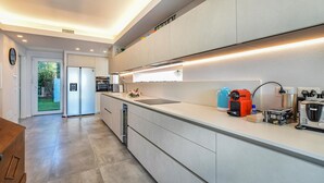 Cozinha moderna com forno embutido, máquina de café e chaleira no balcão.