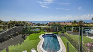 Piscina com vista clara para o mar e montanhas ao longe.