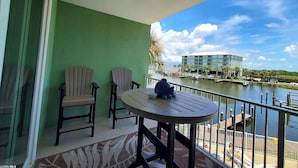 Ein Balkon mit zwei Stühlen und einem Tisch, der auf ein Gewässer und ein Hotelgebäude blickt.
