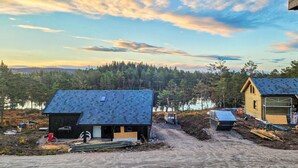 A cabin with a dark roof, surrounded by a forest and a body of water. - Stunning home in Vatnestrøm with sauna (Vatnestrøm)