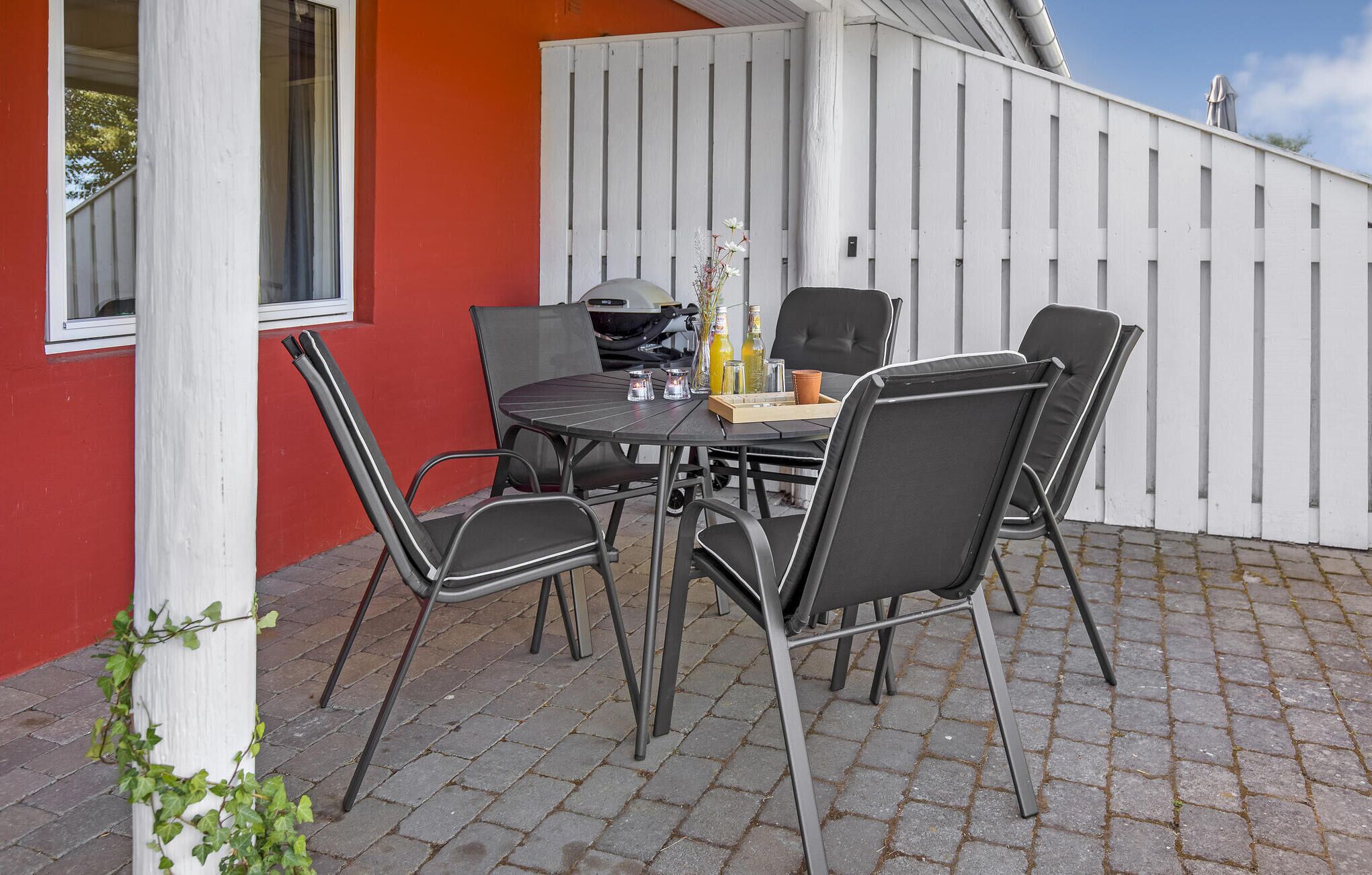 An outdoor patio with a round table, four chairs, and a white fence.