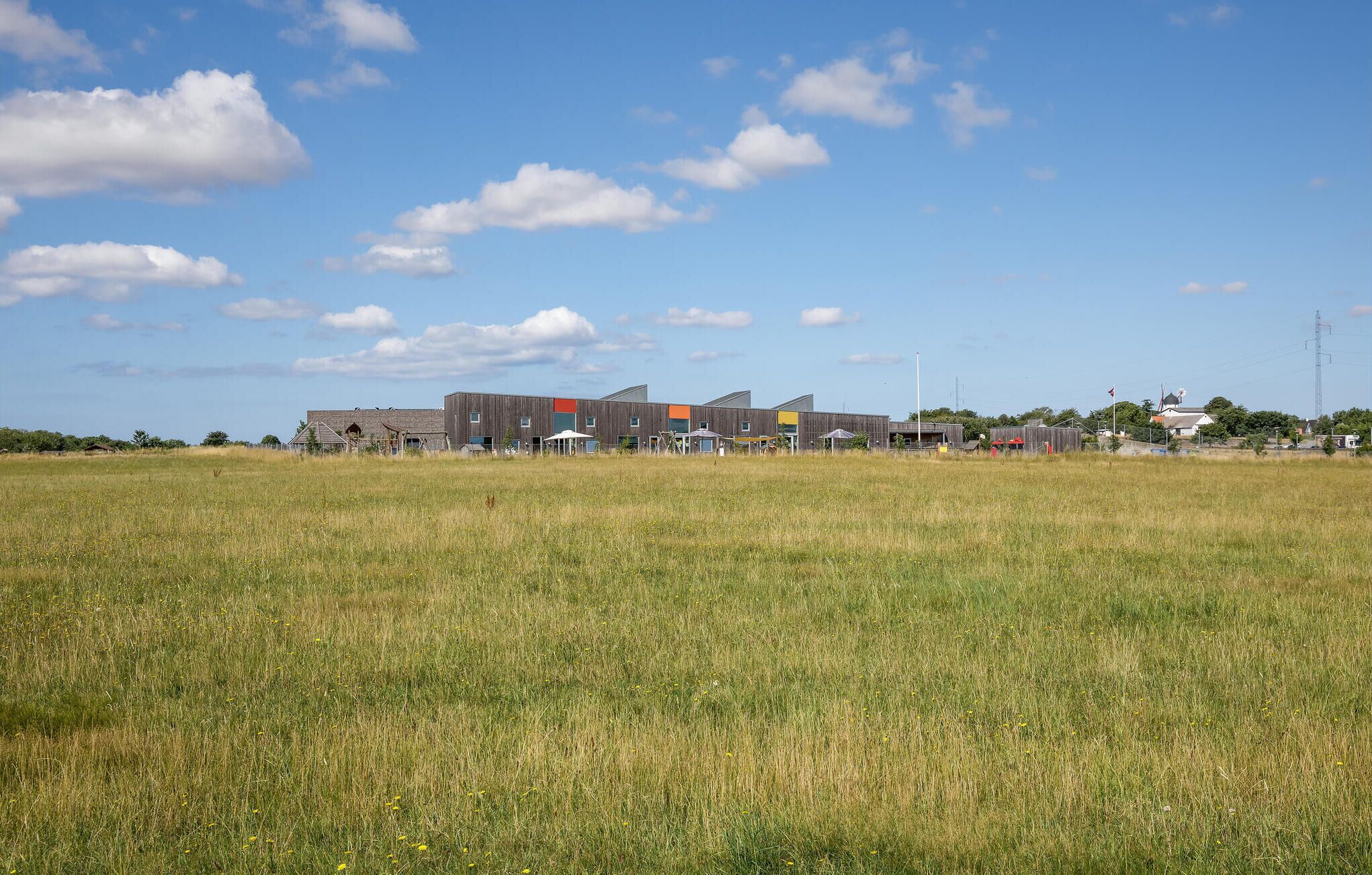 A modern building complex with multiple structures, including a large central building with a flat roof and smaller adjacent buildings.