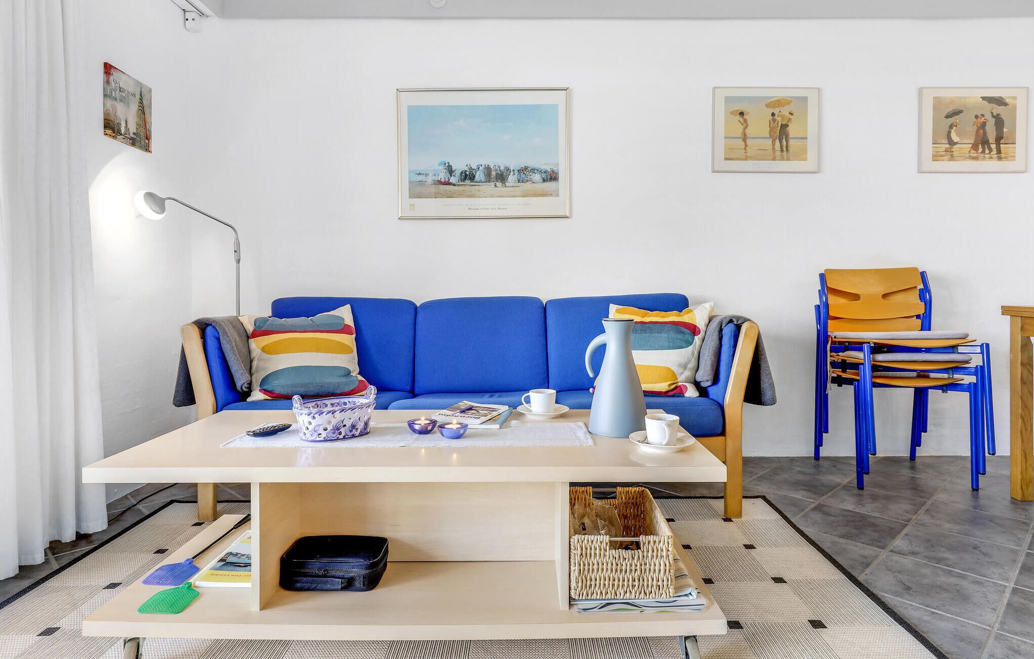 A living room with a blue sofa, a coffee table, a lamp, and a painting on the wall.
