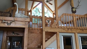 A wooden interior with a staircase, a ceiling fan, and a mounted deer head. - Large beautiful lake front house on Silver Lake MI (Mears)