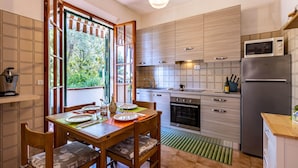 A modern kitchen with wooden cabinets, a built-in oven, and a refrigerator. - Gorgeous apartment in Castiglioncello with WiFi (Castiglioncello)