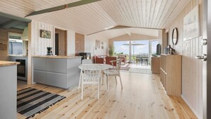 Un vaste espace de vie doté d’un plancher en bois, une cuisine avec un coin bar et une vue sur l’extérieur.