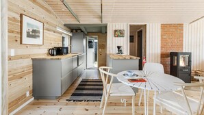 Une cuisine compacte équipée d’un four à micro-ondes, d’une bouilloire et d’une machine à café. Elle comprend un coin repas avec une table et des chaises, ainsi qu’un petit coin salon avec un canapé.